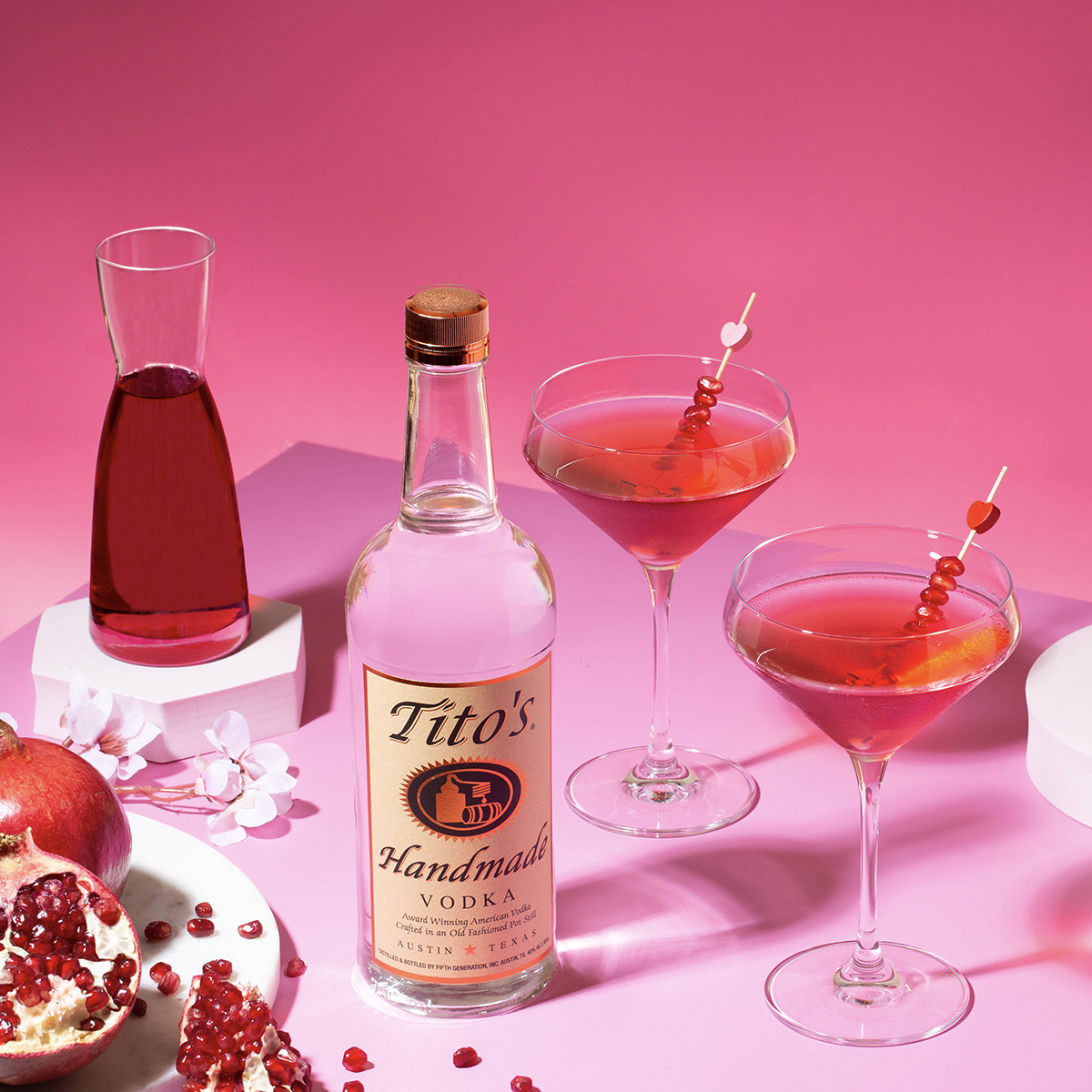 Tito's vodka bottle and cocktails with a pink theme and background